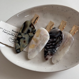 Macro shot of ink texture acetate hair clips with France Handmade lettering in ceramic tray