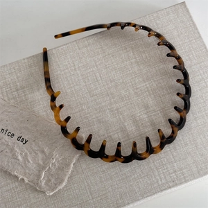 Macro detail of tortoiseshell wavy headband with anti-slip teeth and resin texture