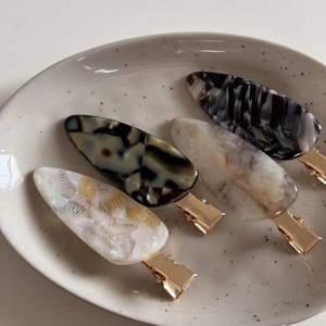 Set of four handmade acetate hair clips with ink textures on a ceramic tray