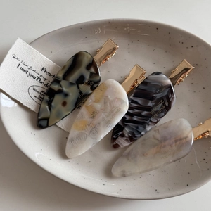 Set of four French minimalist marble and tortoiseshell acetate hair clips in a ceramic bowl
