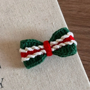 Close-up of handmade crochet Christmas bow hair clip with festive red and green yarn