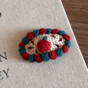 Close-up of handmade crochet Christmas hair clip with red and green wool textures