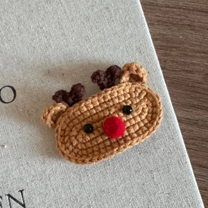 Close-up of handmade crochet reindeer hair clip with detailed knit texture and red pompom nose