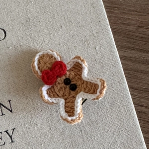 Detailed macro view of handmade crochet gingerbread man hair clip with festive red bow