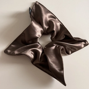 Macro detail of brown silky satin hair scrunchie with soft pleats and stitching