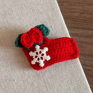 Detail of handmade crochet Christmas sock hair clip with red yarn and white snowflake