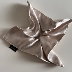 Detailed close-up of champagne silk scrunchie with a Hand Made woven label detail