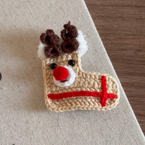 Close-up of handmade crochet reindeer hair clip with cute antlers and red nose for Christmas