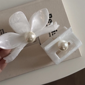 Close-up of cream white acetate hair clips set with pearls and gold metal springs