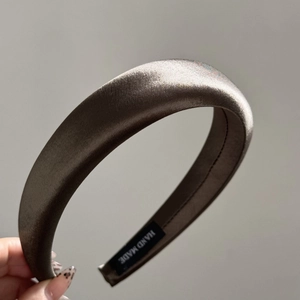 Detail of coffee brown satin headband featuring a hand made label on the inner side