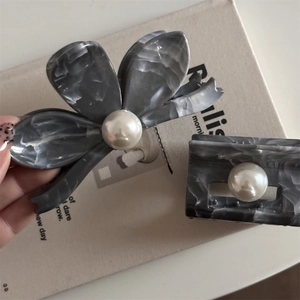 Detail view of marble acetate flower hair claws with elegant pearl accents for women