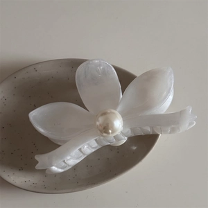 Close-up of a white flower hair claw clip with a glossy pearl center and acetate petals