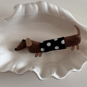 Detail of brown corduroy dachshund hair clip with polka dot fabric in a shell plate