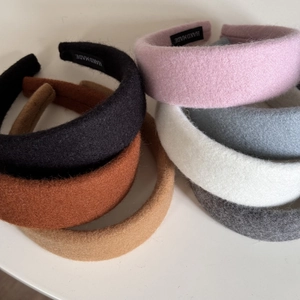 Close-up of fluffy thick headbands in various colors with handmade labels on white background