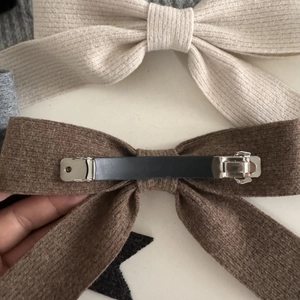 Detail view of knitted bow hair clips in beige and brown with sturdy metal spring fastener
