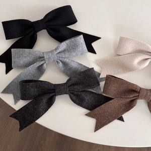 Detail of five-color textured fabric bow hair clips in black, grey, beige and brown
