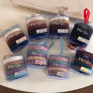 Detailed view of elastic hair bands in transparent boxes on a minimalist white desk