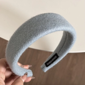 Detail of light grey thick wool headband with handmade label and fuzzy texture