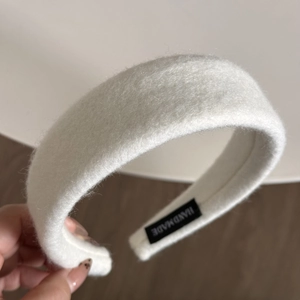Close-up of white plush velvet headband with handmade textile label for autumn winter wear