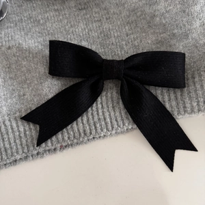 Detailed close-up of the black bow hair clip featuring fine vertical fabric textures