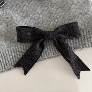 Close-up of the grey fabric bow hair clip showing the detailed knitted wool texture