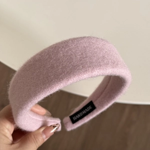 Detail of pink plush headband showing handmade label and soft fuzzy fabric texture