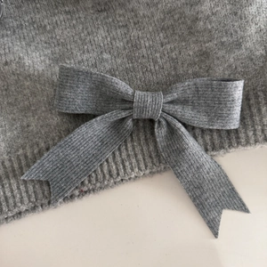 Detailed close-up showing the fine knit texture and bow craftsmanship of the gray hair clip