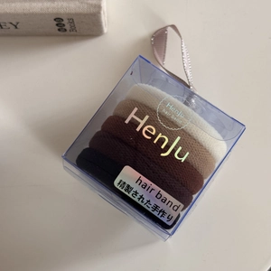 Close-up of five seamless high-elastic hair ties in gradient earthy tones within a clear box