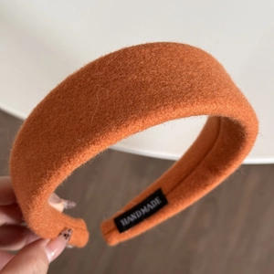 Detail shot of orange wide fabric headband with handmade label and soft wool-like texture