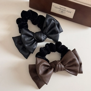 Detailed macro view of high-quality leather and velvet bow hair ties in black and brown