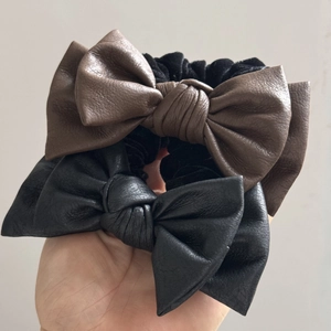 Detailed view of black and brown leather bow scrunchies with fine textured finish