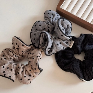 Détail de chouchous à pois beige, gris et noir avec une texture de tissu raffinée