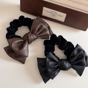 Detail showing faux leather bows and velvet texture on these elegant elastic hair scrunchies