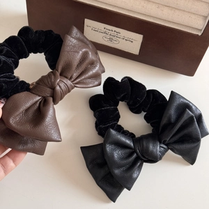 Close-up of leather bow hair ties in brown and black on a vintage jewelry box