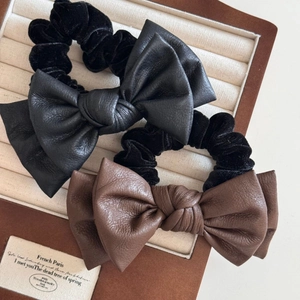 Close-up of leather bow hair scrunchies in black and brown on a jewelry display box