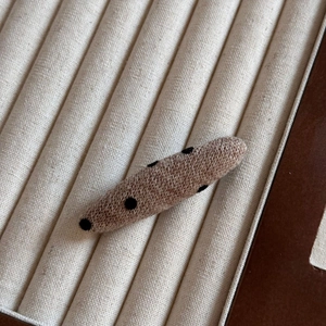 Détail d'une pince à cheveux ovale tricotée avec un motif à pois rétro sur tissu kaki