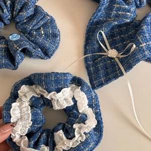 Macro detail of blue tweed scrunchie featuring white lace and ribbon flower accents