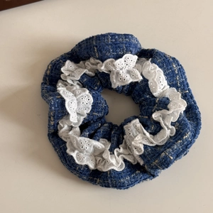 Detail of blue tweed scrunchie with white lace embroidery and vintage button design