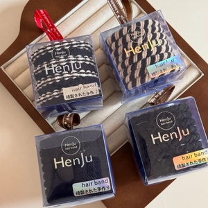 Detail of four high-elasticity hair bands in a branded gift box with silk ribbon