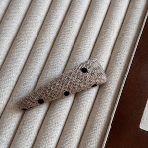 Détail rapproché d'une pince à cheveux en tissu tricoté marron clair à pois noirs doux
