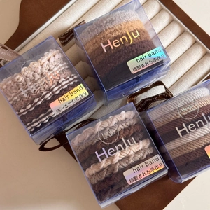 Detail of earth-tone elastic hair ties in transparent boxes with braided texture