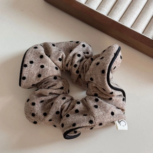 Détail du chouchou en maille beige avec pois noirs et bordure en contraste noire