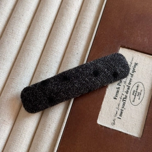 Détail d'une pince à cheveux en tricot gris foncé sur une boîte à bijoux en bois rétro
