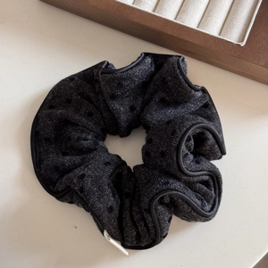 Détail d'un chouchou en maille gris foncé avec texture à pois et bordure noire élégante