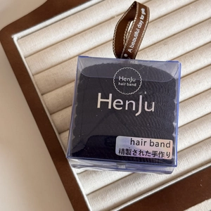 Close-up of black elastic hair ties set in a transparent square box with a brown ribbon