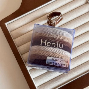 Detail view of high elasticity hair bands in Earth-tone colors within an acrylic box