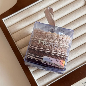 Detail of high-elasticity hair bands in coffee tones within a clear gift box with ribbon
