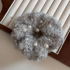 Détail d'un chouchou gris en polaire avec perles élégantes sur un support d'exposition