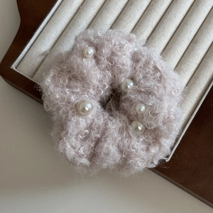 Vue détaillée d'un chouchou en peluche rose avec texture polaire et perles élégantes