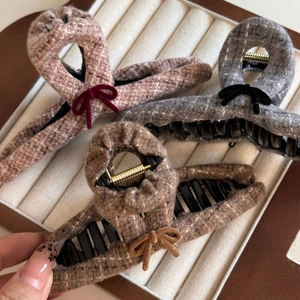 Detailed close-up of tweed bow hair clips in brown and grey on a jewelry tray